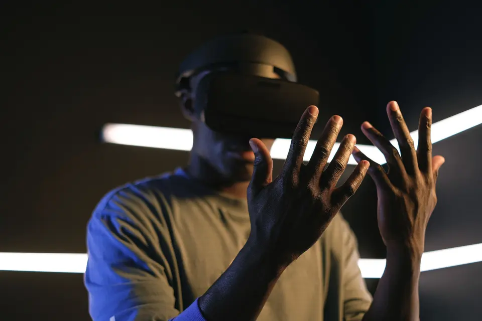 Karanlık odada VR başlığıyla ellerini havada tutan bir kullanıcı